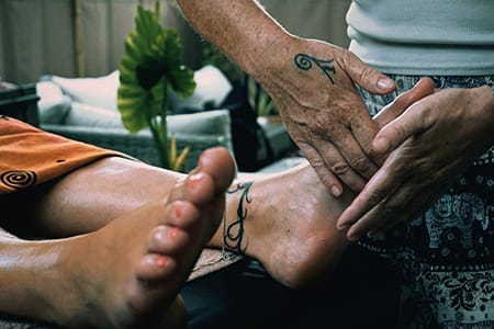 Praticienne réalisant un massage à domicile accès sur la réflexologie plantaire